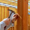 builder hammers a nail into a wooden beam New building home, nailing hammer